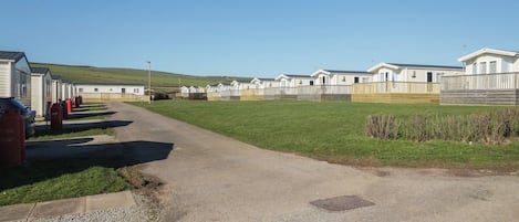 A caravan park with a gravel path leading to multiple caravans, a grassy area, and a clear sky.