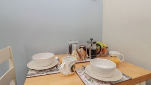 A breakfast table with white plates, a mug, and a glass of orange juice. - Bumble Bee Lodge (Filey)