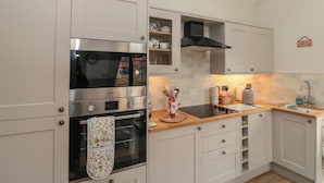 A kitchen with a built-in oven, a microwave, and a window above the sink. - Bumble Bee Lodge (Filey)