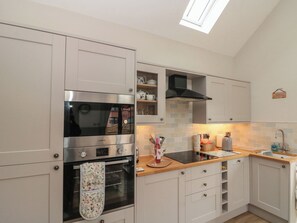 A kitchen with a built-in oven, a microwave, and a window above the sink. - Bumble Bee Lodge (Filey)