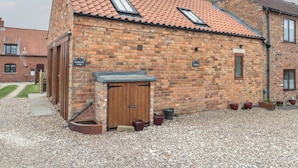 A brick building with a tiled roof, a wooden door, and a small window. - Bumble Bee Lodge (Filey)