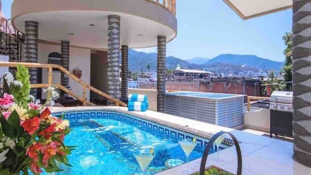 Una piscina sul tetto con vista sulle montagne, una zona salotto riparata e un barbecue.