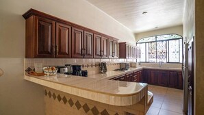 Una cucina con mobili in legno, un piano di lavoro in marmo e un'ampia finestra.