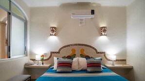 Camera d'albergo con un letto, due comodini, una finestra, un condizionatore d'aria e luci a parete.