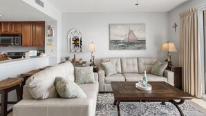 A living room with a sofa, coffee table, and a painting of a sailboat.