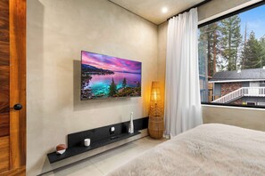 A bedroom with a large window, a painting of a landscape, a bedside table, and a fluffy rug. - South Lake Tahoe 2 Bedroom (South Lake Tahoe)