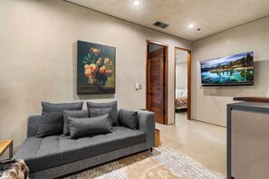 A living room with a grey sofa, a painting of flowers, and a TV displaying a scenic landscape. - South Lake Tahoe 2 Bedroom (South Lake Tahoe)