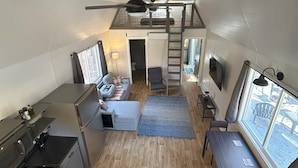 Una cucina compatta con zona pranzo, un piccolo soggiorno e una camera soppalcata con vista.