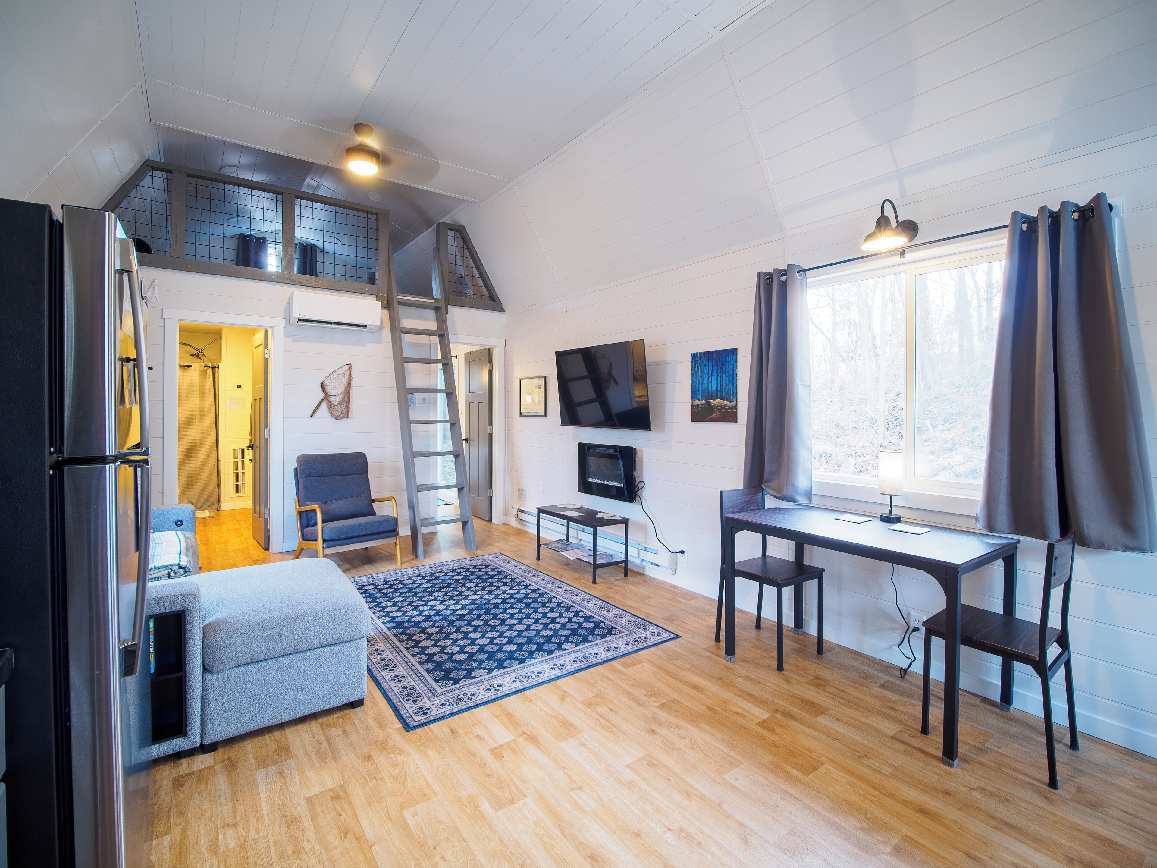 A compact living space with a loft bedroom, a dining area, and a seating area.