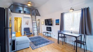 A compact living space with a loft bedroom, a dining area, and a seating area.