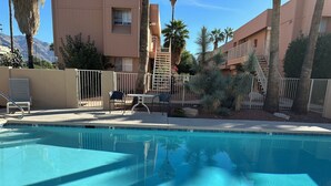 Une piscine à l’eau d’un bleu limpide, entourée d’une clôture et jouxtant un bâtiment doté d’un escalier.
