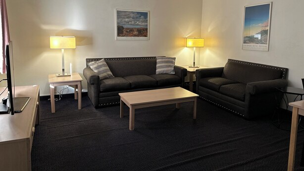 Une chambre d’hôtel avec deux canapés, une petite table, deux lampes et deux tableaux encadrés accrochés aux murs.