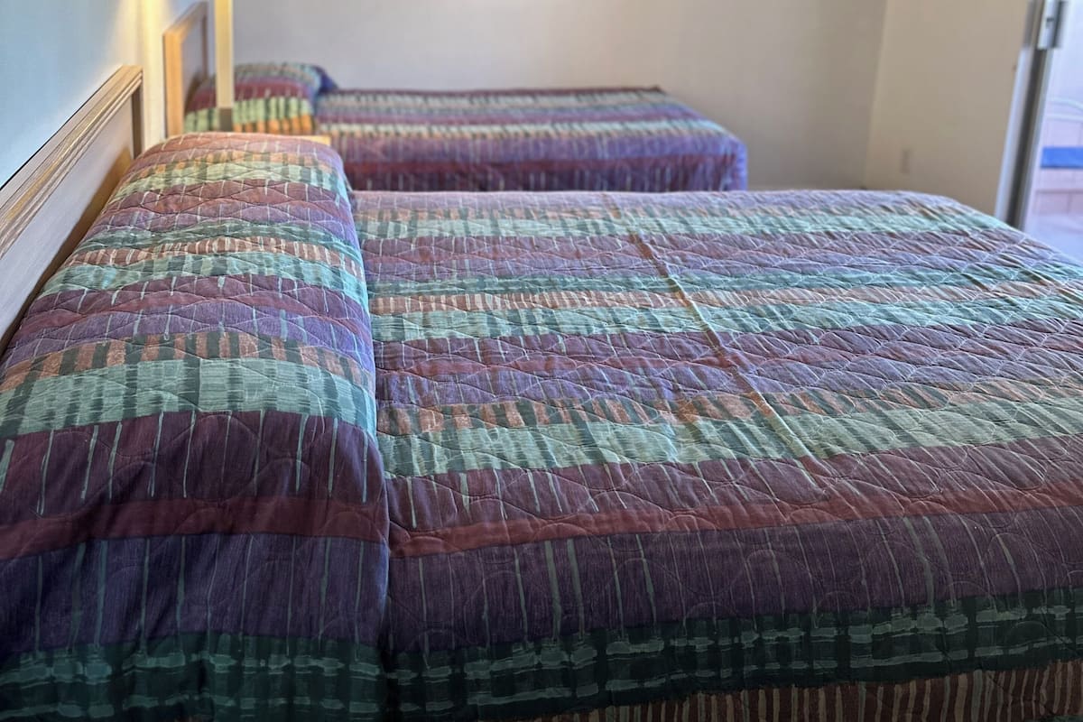 Ένα δωμάτιο ξενοδοχείου με δύο κρεβάτια, μια αφίσα στον τοίχο και ένα φωτιστικό.
