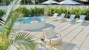 A pool area with a hot tub, lounge chairs, and a palm tree. - Mediterranean-style Home Near Design District With a Pool! (Miami)