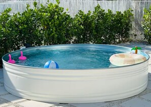 Een ronde hottub met glazen wanden, omringd door een betegeld terras.