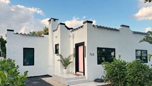 A white building with a black door, numbered 745, and a small garden area. - Mediterranean-style Home Near Design District With a Pool! (Miami)