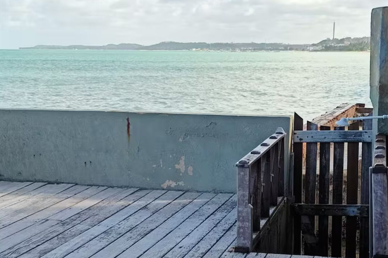 A wooden deck with a metal railing overlooking a body of water.