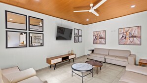 Un salon moderne avec un canapé, une table basse, un téléviseur et des œuvres d’art accrochées aux murs.