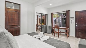Une chambre d’hôtel avec un lit, un bureau, une chaise et une armoire.