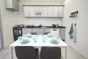 Une cuisine de taille réduite avec des meubles blancs, un four à micro-ondes, une cuisinière et un évier.