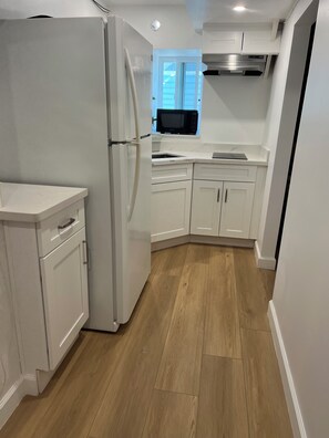 A kitchen with white cabinetry, a refrigerator, a microwave, and a sink. - Delightful 1-bedroom studio in Daly City perfect for your getaway (Daly City)