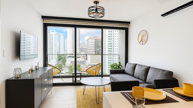 Un appartement moderne doté d’une grande fenêtre, d’un canapé, d’une table à manger et d’un téléviseur.