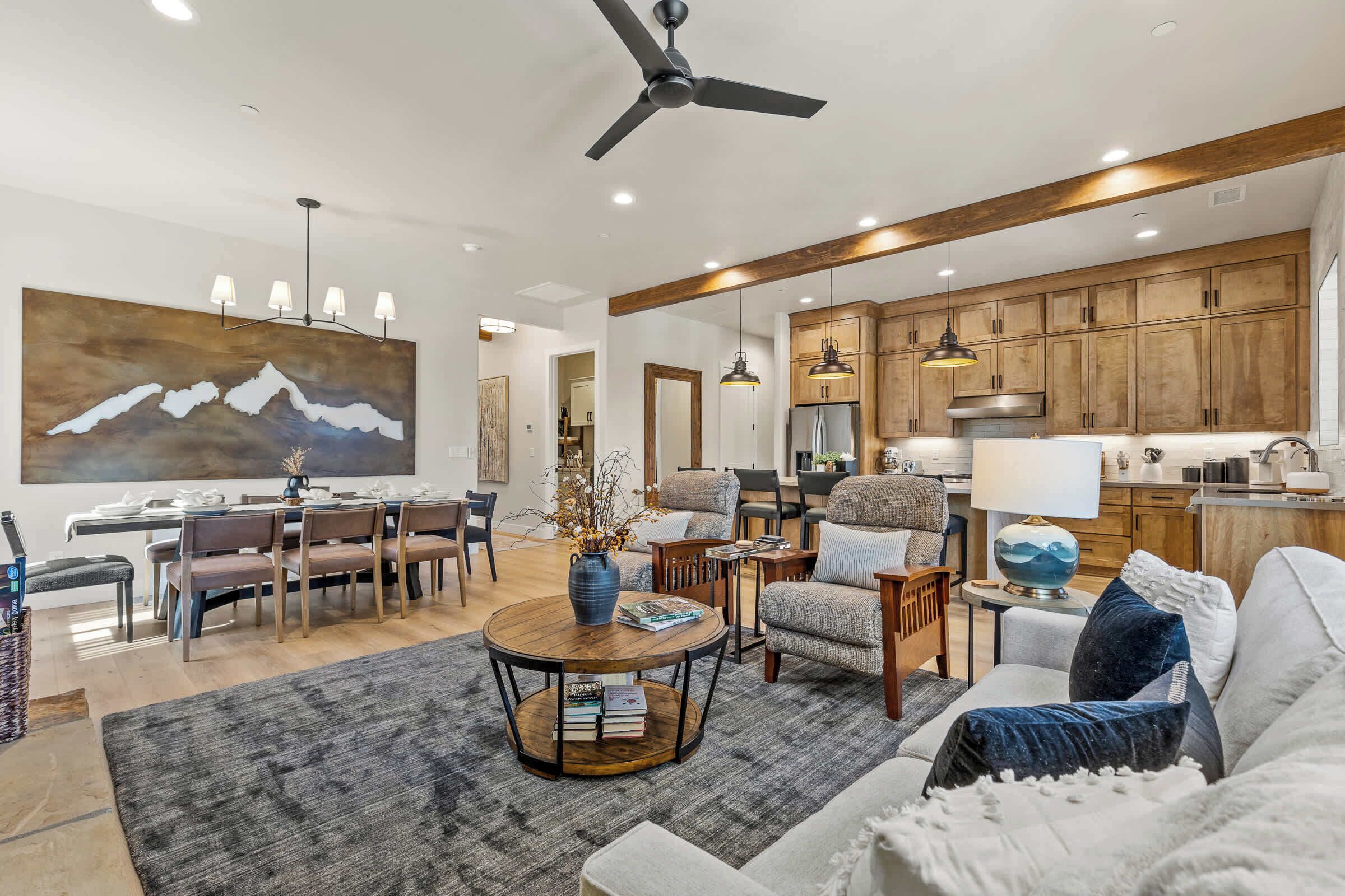 A modern living room with a dining area, wooden cabinets, and a large painting.