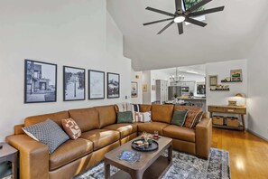 A living room with a brown leather sofa, a coffee table, and framed pictures on the wall. - NEW! | Kachina Cabin | AC | Trail Access | Hot Tub (Flagstaff)