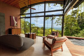 A modern interior with a large window, a sofa, a wooden table, and a chair.