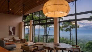 Amplia habitación con un gran ventanal que ofrece una vista panorámica, una mesa redonda de madera y asientos cómodos.