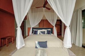 A bedroom with a bed, canopy, and a ceiling fan.