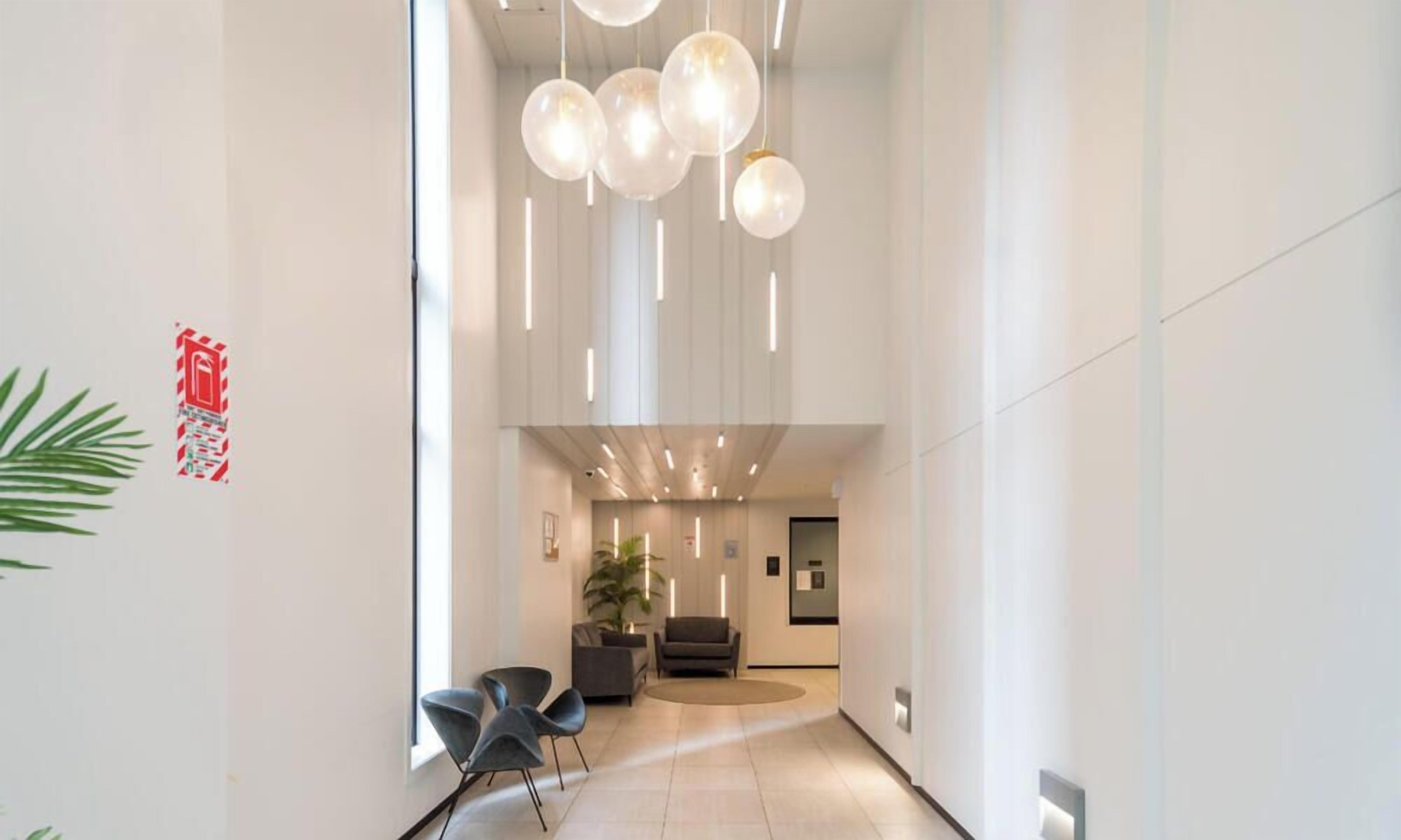 A modern interior with a reception area, seating, and a plant.