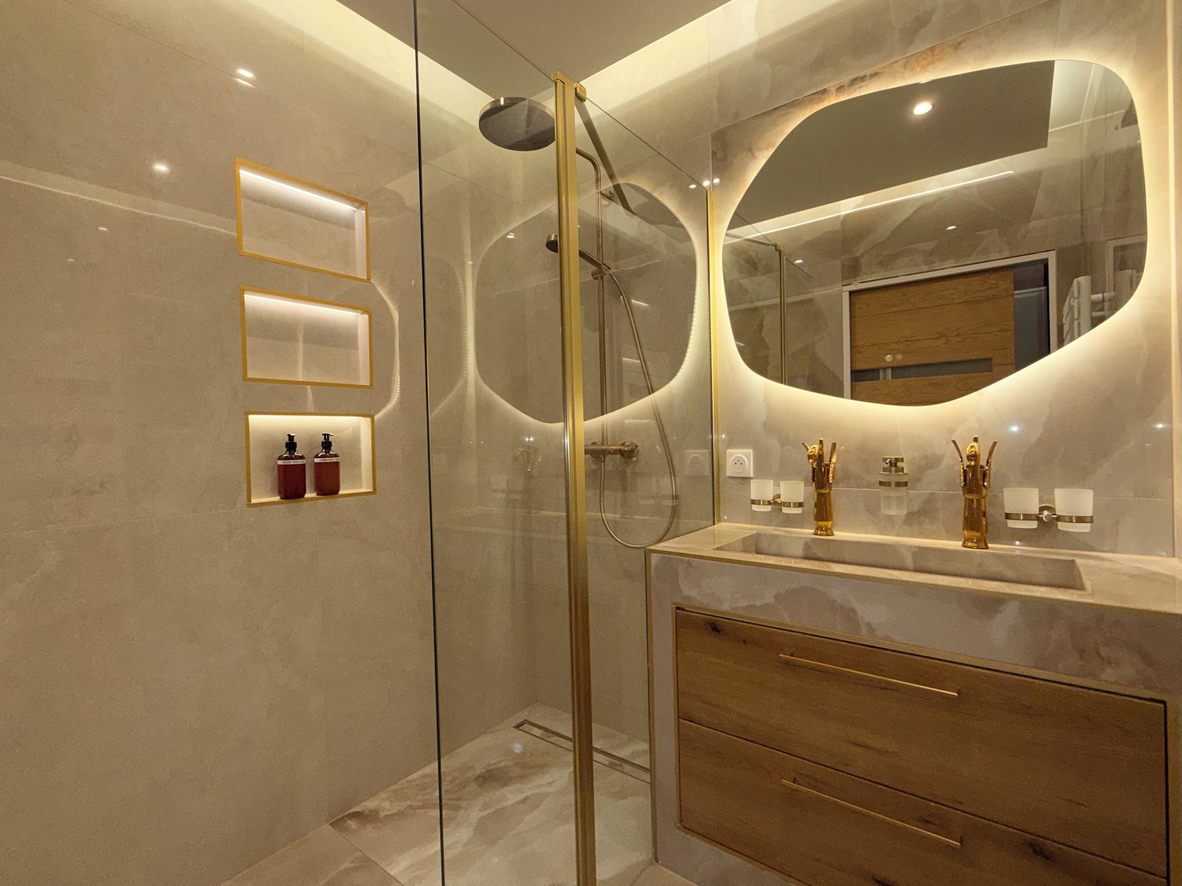 Un baño moderno con cabina de ducha de vidrio, un espejo grande y encimera de mármol.