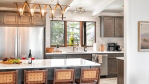 A modern kitchen with a central island, stainless steel appliances, and a large window providing natural light. - Biltmore Ridgetop Escape | Hot Tub + Sauna (Asheville)
