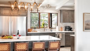 A modern kitchen with a central island, stainless steel appliances, and a large window providing natural light. - Biltmore Ridgetop Escape | Hot Tub + Sauna (Asheville)