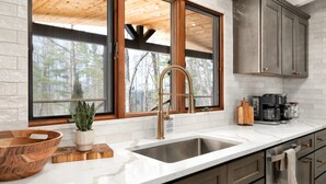 A kitchen with a large window, a stainless steel sink, wooden cabinets, and a coffee maker. - Biltmore Ridgetop Escape | Hot Tub + Sauna (Asheville)