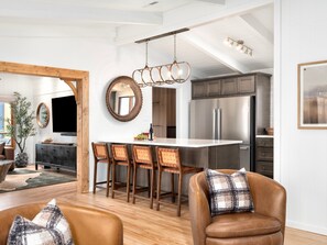 Una cocina moderna con una isla central, electrodomésticos de acero inoxidable y un comedor con sillas de madera.