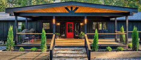 A modern building with a red door, wooden deck, and a covered entrance.