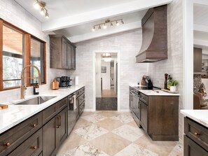 A modern kitchen with white subway tiles, dark wood cabinets, and a marble floor. - Ridgetop Lodge | Hot Tub, Sauna & Red Stag Lounge (Asheville)