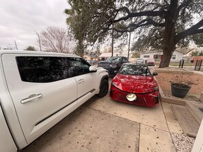 A residential driveway with two parked cars, a large tree, and a house in the background. - Oak Canopy Cottage, Near Downtown, Lackland, & More (San Antonio)