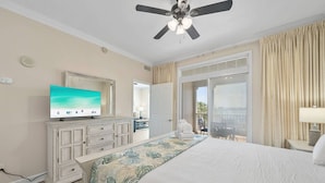 A hotel room with a bed, a television, a ceiling fan, a large window, and a view of the outdoors. - New Listing: Luxury Resort Condo | Bay Views, Lagoon Pool, Golf, Spa & More! (Panama City Beach)