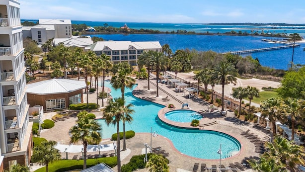 A resort with a large pool, palm trees, and a view of the ocean. - New Listing: Luxury Resort Condo | Bay Views, Lagoon Pool, Golf, Spa & More! (Panama City Beach)