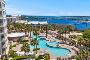 Un resort con una gran piscina, palmeras y vista al océano.
