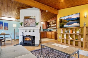 Ein gemütliches Wohnzimmer mit Kamin, Holzregalen und einem großen Landschaftsbild.