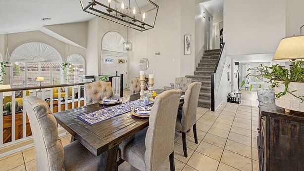 A dining area with a wooden table, upholstered chairs, and a chandelier. - Private Pool Near Thunderbird Park (Glendale)
