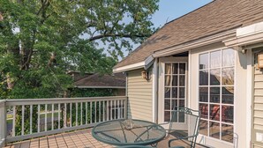 A wooden deck with a metal table and chairs, a white railing, and a house with a window and door. - Riverfront Suites • Fireplace • Whirlpool for Two • Walk to Downtown (Wisconsin Dells)