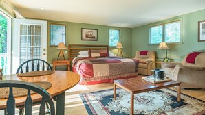 A bedroom with a bed, two chairs, a table, and a window. - Riverfront Suites • Fireplace • Whirlpool for Two • Walk to Downtown (Wisconsin Dells)