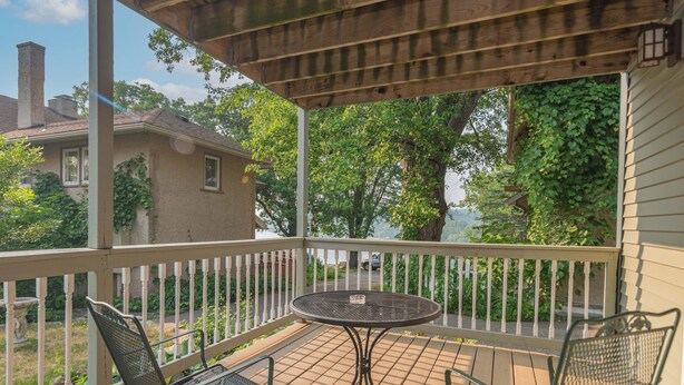 A covered outdoor area with a table and chairs, a view of a house, and a tree. - Riverfront Suites • Fireplace • Whirlpool for Two • Walk to Downtown (Wisconsin Dells)