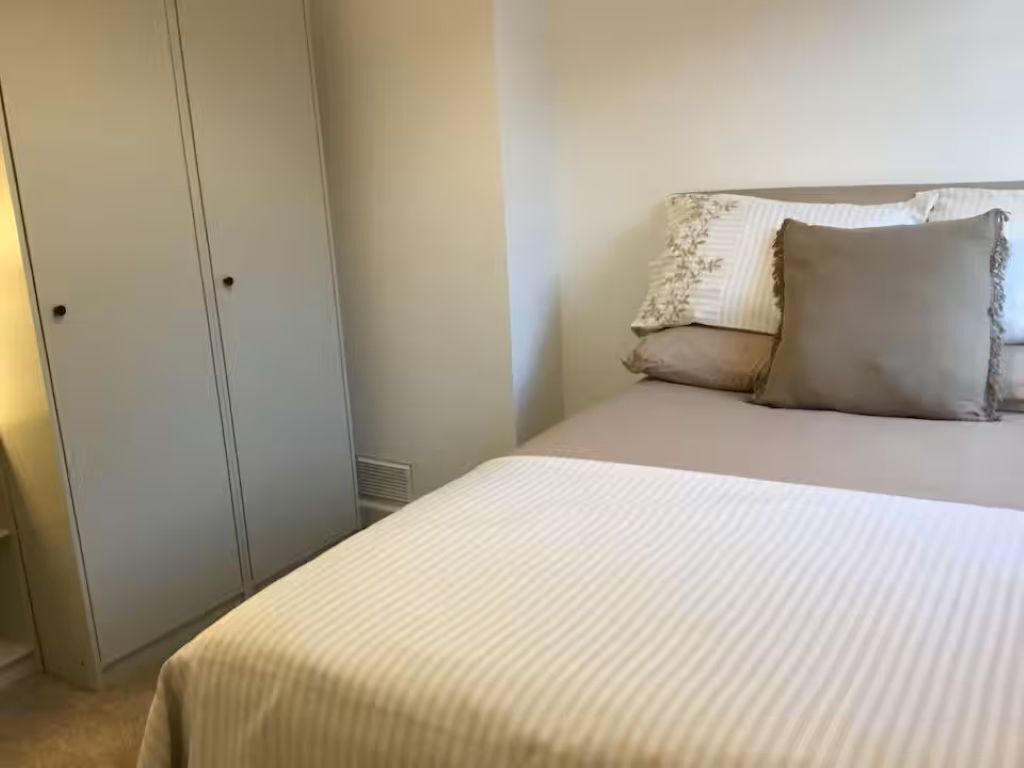 Een slaapkamer met een bed, een kledingkast en een nachtkastje.