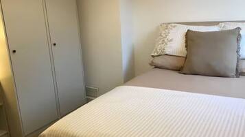 Een slaapkamer met een bed, een kledingkast en een nachtkastje.